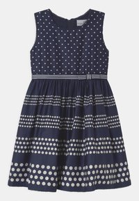 Merkkimekko ilman hihoja, jossa on valkoisia pilkkuja ja raidalliset yksityiskohdat vyötäröllä. Silkkinen rakenne, polveen saakka ulottuva leikkaus.