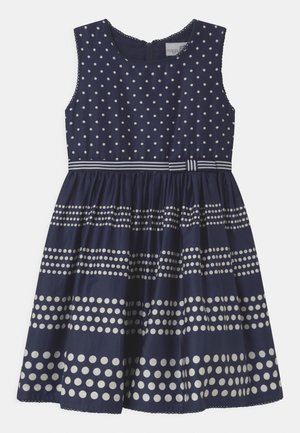 Námořnické šaty bez rukávů, zdobené bílými puntíky a pruhovanými akcenty kolem pasu. Hladká textura, délka po kolena.