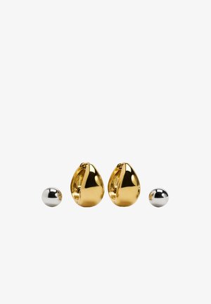 Kolczyki z metalu w kolorze złota w kształcie kropli, z polerowaną, refleksyjną powierzchnią, obok małej, srebrnej kulki.