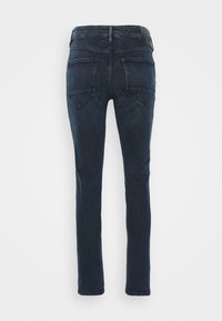 Tmavě modré slim fit džíny zobrazené ze zadní strany se dvěma zadními kapsami a koženou značkovou nášivkou na pase.