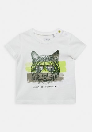 Wit peuter-T-shirt met een afbeelding van een kat met reflecterende zonnebril, op een achtergrond van gele en bruine penseelstreken, met daaronder de tekst "KING OF TOWN/IKKS".