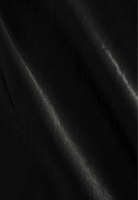 Mustmustekangas sileda tekstuuri ja peen sära, pehme lohkumise ja kergete voldidega, mis viitab kergale materjalile.