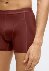 Μπορντό εσώρουχα τύπου μποξέρ από ομαλό, ελαστικό ύφασμα. Διαθέτουν εφαρμοστή σχεδίαση με λογότυπο στη ζώνη μέσης και αντιθετικές ραφές.