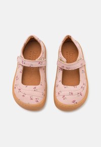 Rozā Mary Jane kurpes ar ziedu rakstu uz mīksta auduma virsmas, ar apaļu pirkstu daļu, Velcro siksniņu un teksturētu gumijas zoli.