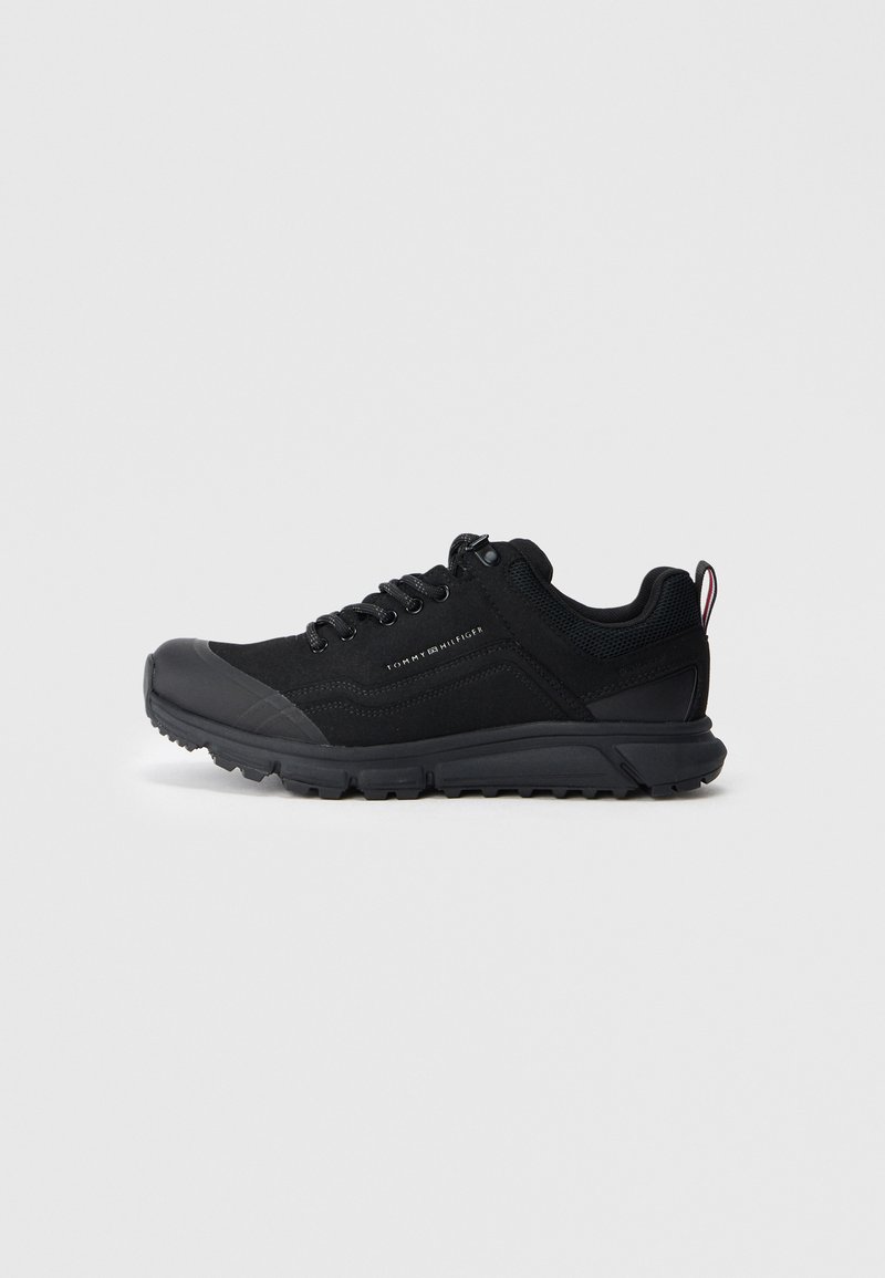 Sapatos de atletismo pretos com um cabedal em tecido texturizado, biqueira de borracha e design de atacadores. Apresentam uma sola robusta e uma marcação discreta.