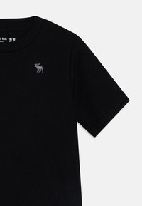T-shirt nera in cotone con maniche corte e scollatura rotonda, dotata di un piccolo alce grigio ricamato sulla zona sinistra del petto.