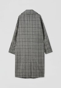 Musta-valkoinen ruudullinen takki, jossa on kaulus, pitkät hihat ja rento istuvuus. Kankaan pintakuvio on ruudullinen, ja viivojen paksuus vaihtelee.