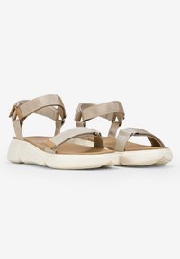 Sandalias beige con correas de tela ajustables, plantilla acolchada y suela de goma blanca con un ligero diseño curvado.
