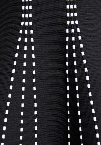 Un tissu noir présente des lignes blanches en pointillé formant des motifs verticaux. La texture semble lisse avec un léger éclat.