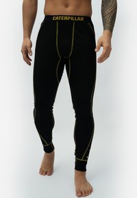 Black thermal leggings with yellow stitching and a yellow "CATERPILLAR" logo on the waistband. Fitted design with a smooth texture.
