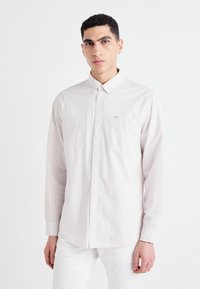 Light striped button-up shirt in soft fabric; features a collar, long sleeves, and a chest pocket with a logo accent.