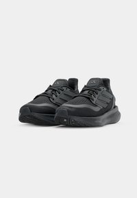 Black athletic shoes with a textured mesh upper, cushioned sole, and three stripe accents. Features laces and a reinforced heel.