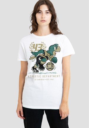 Young woman wearing white T-shirt with cartoon bird playing soccer and text "Athletic Department Zé Carioca Est. 1943" on front.