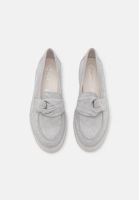 Graue Wildleder-Lederschuhe mit einem geknoteten Akzent auf dem Blatt, abgerundeter Zehenform und kontrastierender Naht entlang der Sohle. Weiche Textur und minimales Design.