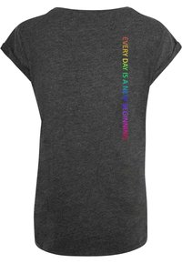 Graues T-Shirt mit kurzen Ärmeln und lockerer Passform. Auf der Rückseite steht in Regenbogenfarben der Text "JEDER TAG IST EIN NEUER BEGIN" vertikal.