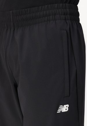 Svarta träningsbyxor med elastisk midja, sidoficka och vitt New Balance-logotyp på låret.