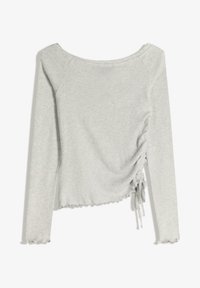 Dlhý rukáv, top bez ramienok v svetlosivej bavne. Má nahrnutú textúru na jednej strane a zúbkovaný lem.