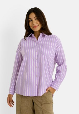 Camisa de botones de color púrpura claro con rayas verticales blancas, que cuenta con un cuello, mangas largas y un bolsillo en el pecho. Tejido texturizado.
