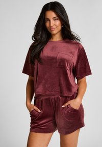 Bordeaux fluwelen loungewear set bestaande uit een boxy top met korte mouwen en een borstzak, en losse shorts met zijzakken.
