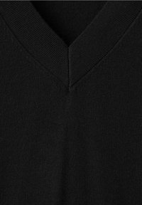 Gros plan d'un tissu noir tricoté montrant un col en V avec une texture côtelée fine et une couture sans couture.