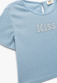 Camiseta de algodón de manga corta en azul claro con escote redondo. Presenta el texto "Kiss" en strass en la parte delantera. Tejido suave y texturizado.