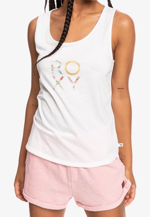 Un débardeur blanc présente un logo floral "ROXY" en couleurs multiples. Associé à un short rose doux avec ourlet roulé. Le tissu semble léger et confortable.