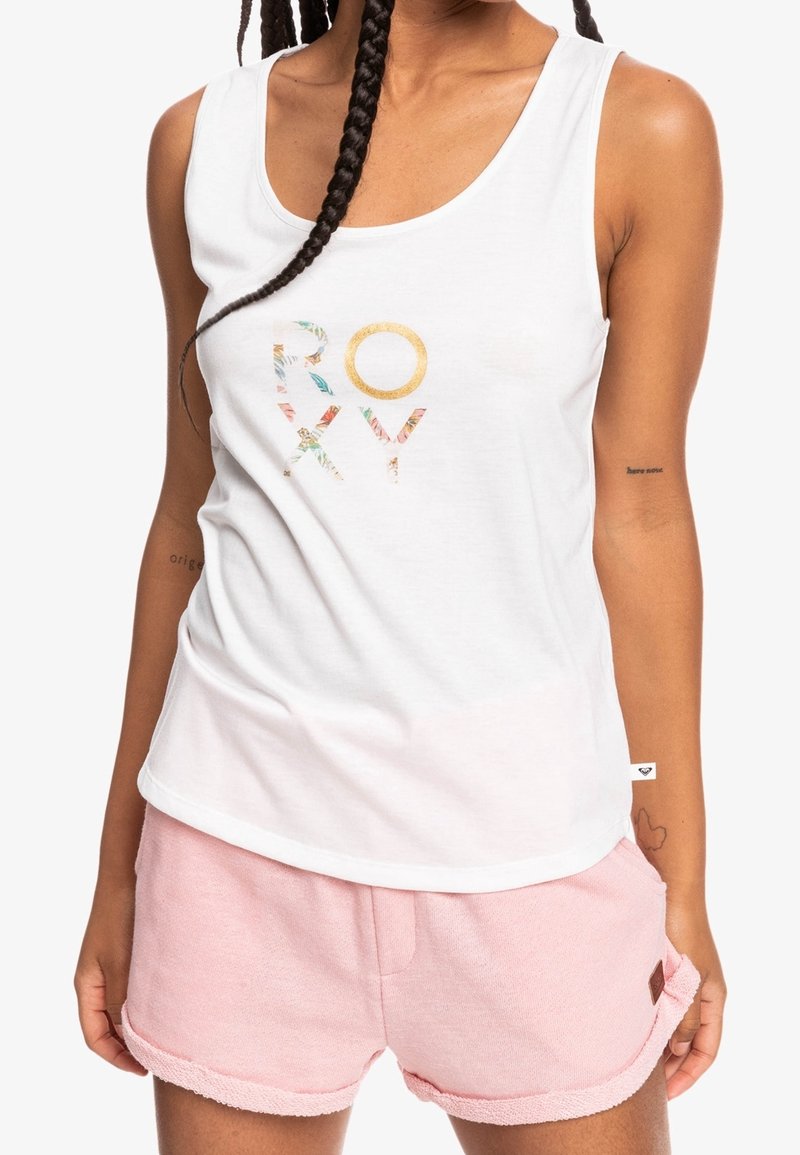 Un débardeur blanc présente un logo floral "ROXY" en couleurs multiples. Associé à un short rose doux avec ourlet roulé. Le tissu semble léger et confortable.