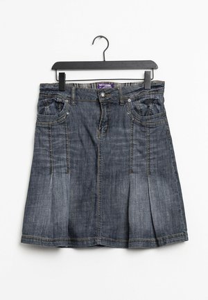 Jupe trapèze en denim avec plis, poches avant, passants pour ceinture et fermeture par boutons, suspendue à un cintre en plastique noir sur fond blanc.
