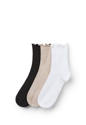Sada tří kotníkových ponožek s volánkovými lemy v černé, béžové a bílé barvě, rozložených na bílém pozadí.