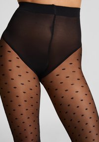 Zwarte doorschijnende panty’s met een hoge tailleband, voorzien van een stippenpatroon. Het materiaal is glad en semi-transparant, met een naadloos ontwerp.