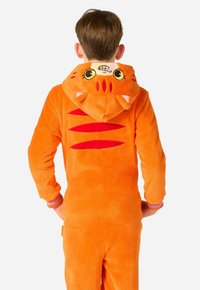 Oranžna flis pjama z kapuco, ki vključuje risanko mačke z aplikacijami za oči in ušesa ter rdečimi poudarkami na hrbtu. Rebrasti manšeti.
