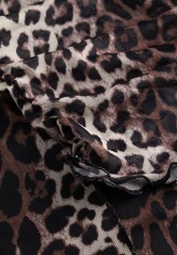 Tessuto con stampa leopardata che mostra macchie marroni, beige e nere con trama visibile e bordi cuciti.