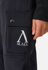 Czarne spodnie cargo z tkaniny z wyraźnym białym logo "SLADE". Zawierają zapięcie na zatrzask i teksturowane detale wykończenia na kieszeniach.