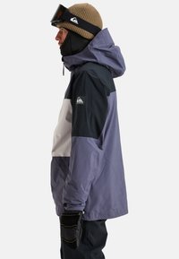 Heren geïsoleerde jas in paarse, zwarte en witte kleurblokken. Heeft een capuchon, elastische manchetten en logo detail op de mouw. Getextureerde handschoenen.