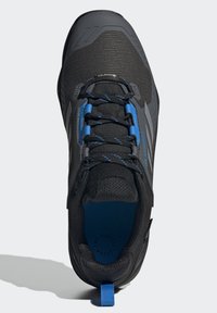 Czarne buty sportowe z siateczkowej cholewki, niebieskimi sznurowadłami i teksturowanym językiem. Pętla na pięcie ułatwiająca zakładanie, lekkie wzornictwo.