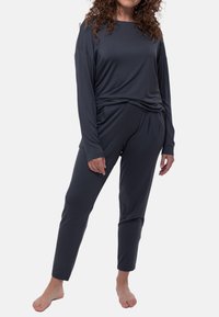 Set da soggiorno grigio scuro composto da una maglietta a manica lunga con vestibilità rilassata e pantaloni affusolati, entrambi realizzati in tessuto morbido e leggero.