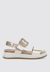 Sandalias metálicas doradas y crema con una correa ancha, hebilla ajustable y suela acolchada. Material texturizado con un acabado suave.