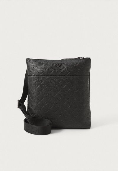 Czarna torebka crossbody wykonana z teksturowanego materiału syntetycznego. Posiada zamek błyskawiczny, regulowany pasek i wytłoczone logo z przodu.