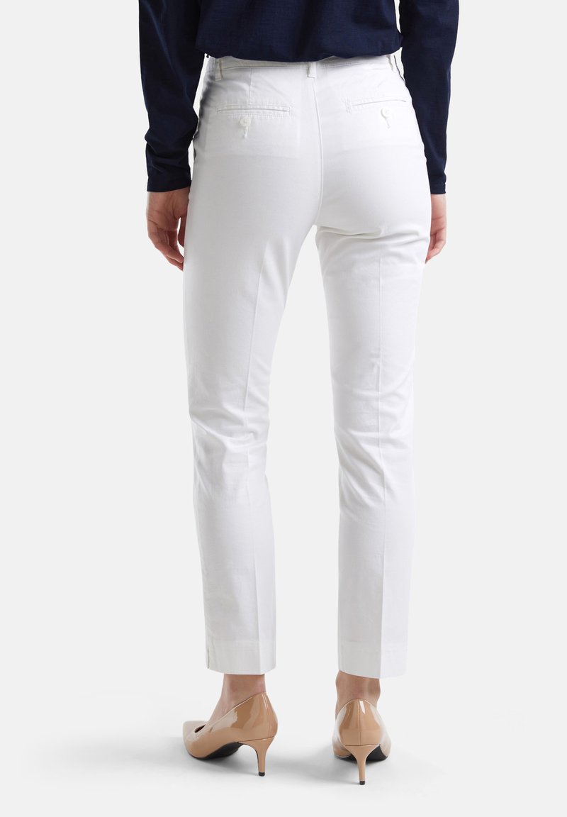 Weiße, taillierte Hosen mit Slim-Fit, ausgestattet mit Gesäßtaschen und einer glatten Textur, kombiniert mit beigen High Heels.