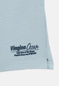 Šviesiai mėlyna, tekstūruota medžiaga su tamsiai mėlynai atspausdintu tekstu: "Vingino Ocean" su šūkiu apie jūros priežiūrą ir gilių jūrų programas.