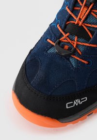 Marineblå nubuck vandresko med orange accenter, sort gummisål, struktureret mesh-tunge og sikker snøresystem for en tæt pasform.