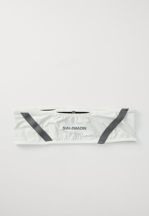 Bandeau en tissu blanc avec des accents élastiques noirs et des côtés froncés, arborant la marque "SALOMON" en lettres sombres à l'avant.
