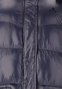 Marinblå puffjacka med en glansig, slät yta. Har dragkedja fram och stickade detaljer. Svart logotyp på övre vänstra sidan.