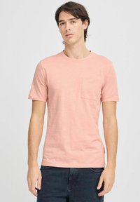 Camiseta de algodón rosa claro con mangas cortas y un bolsillo en el pecho, con un escote redondo y un corte holgado.