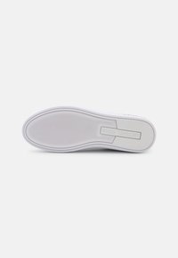 Suela de zapatilla blanca con agarre texturizado, bordes suaves y un logotipo sutil. Presenta una punta redonda y una entresuela en contraste.