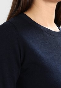 Su�éter de color azul marino, de punto, con un cuello redondo y mangas largas, que presenta una textura suave y un diseño casual versátil.