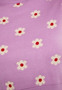 Pulover lila cu o textură tricotată, împodobit cu flori albe și centre roșii, dispuse uniform pe întreaga țesătură. Model floral simplu și repetitiv.