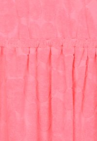 Růžová látka s texturovaným vzorem, která obsahuje měkké vyvýšené tečky a sklady podél švu, vytvářející vrstvený efekt.