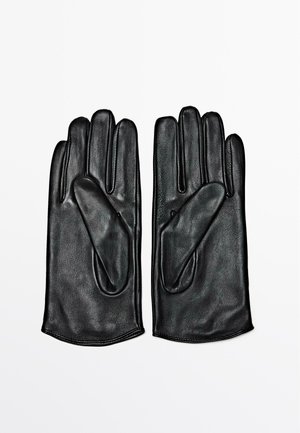 Guanti in pelle nera, caratterizzati da una superficie liscia, design aderente e cinque dita con cuciture rinforzate, presentati distesi su uno sfondo bianco.