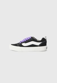 Sneaker nera in suede con striscia laterale bianca, lacci viola e suola in gomma bianca. Presenta un interno con motivo e logo sul tallone.